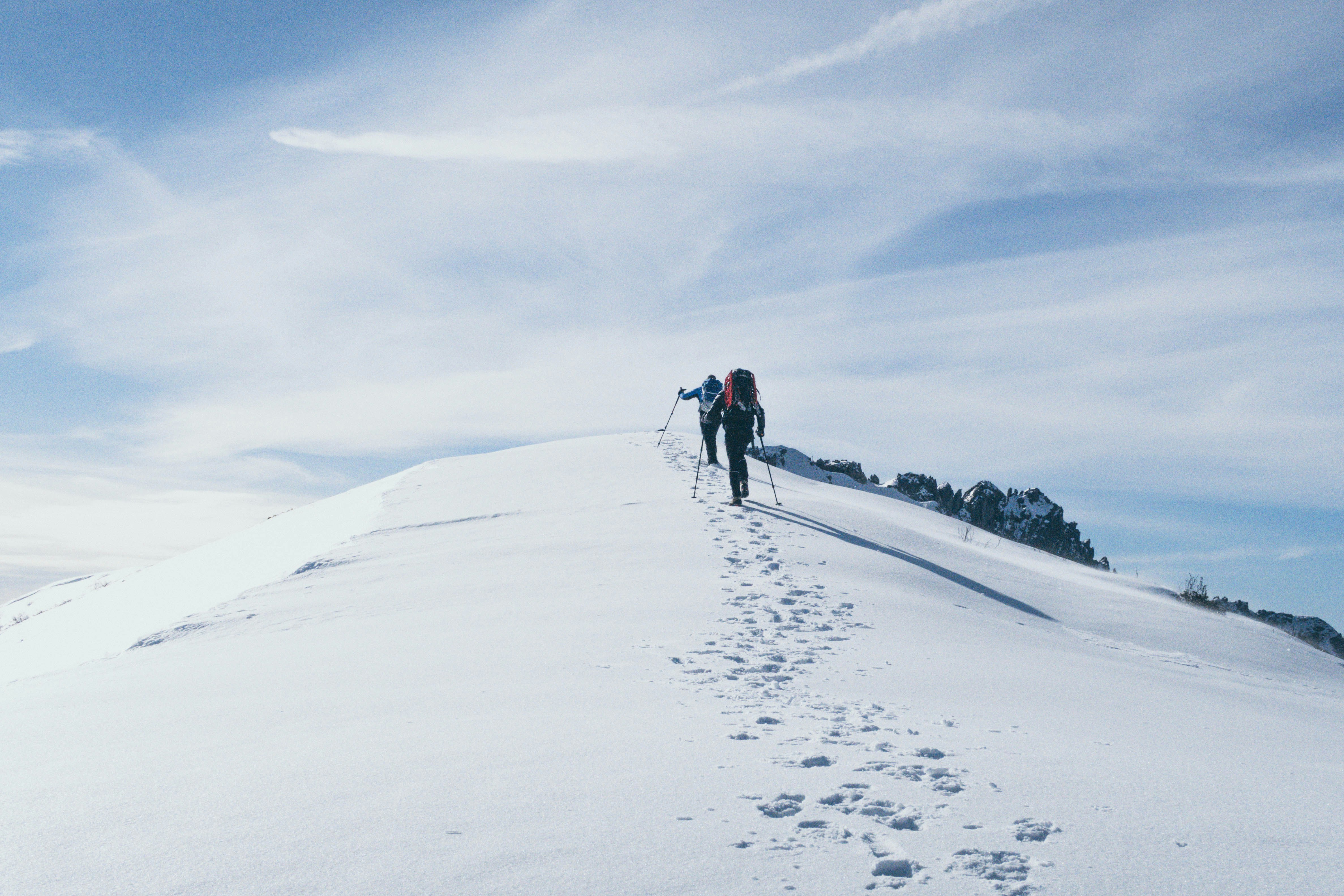 Two mountaineers ascending a snow-covered ridge line
